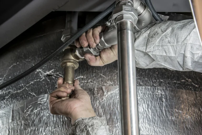 Plumber repairing a water supply pipe indoors